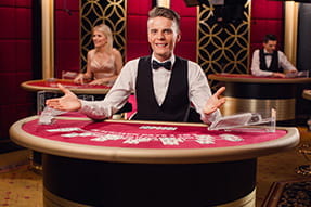 En mandlig dealer sidder ved et bord med åbne arme og er klar til spil.