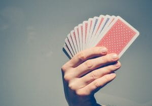 Hånd der holder et sæt spillekort op i luften.
