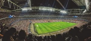 Fodboldstadium med fyldt publikum og spillere på banen.