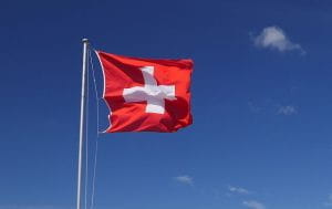 Et hejst schweizisk flag med en blå himmel i baggrunden.