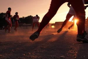 Fodboldspillere på en fodboldbane, hvor solen er ved at gå ned.