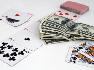 Spillekort og en bunke pengesedler på en hvid overflade.