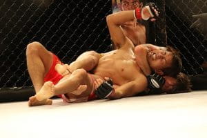 To MMA-kæmpere ligger på gulvet i en kamp.