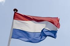Det hollandske flag der vejrer i luften med en blå himmel som baggrund.