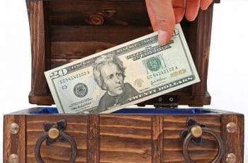 En trækiske og en hånd tager penge op fra kisten.